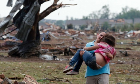 A woman carries a child through a field near the collapsed Plaza Towers elementary school in Moore, Oklahoma.